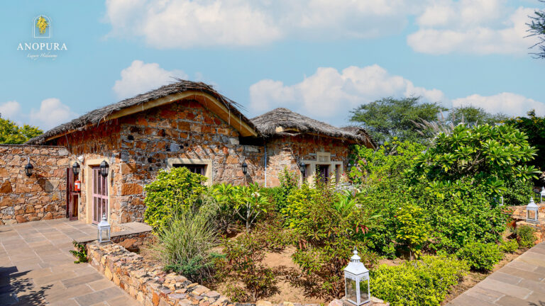 stone cottages surrounded by lush gardens at Anopura Luxury Hideaway Jaipur